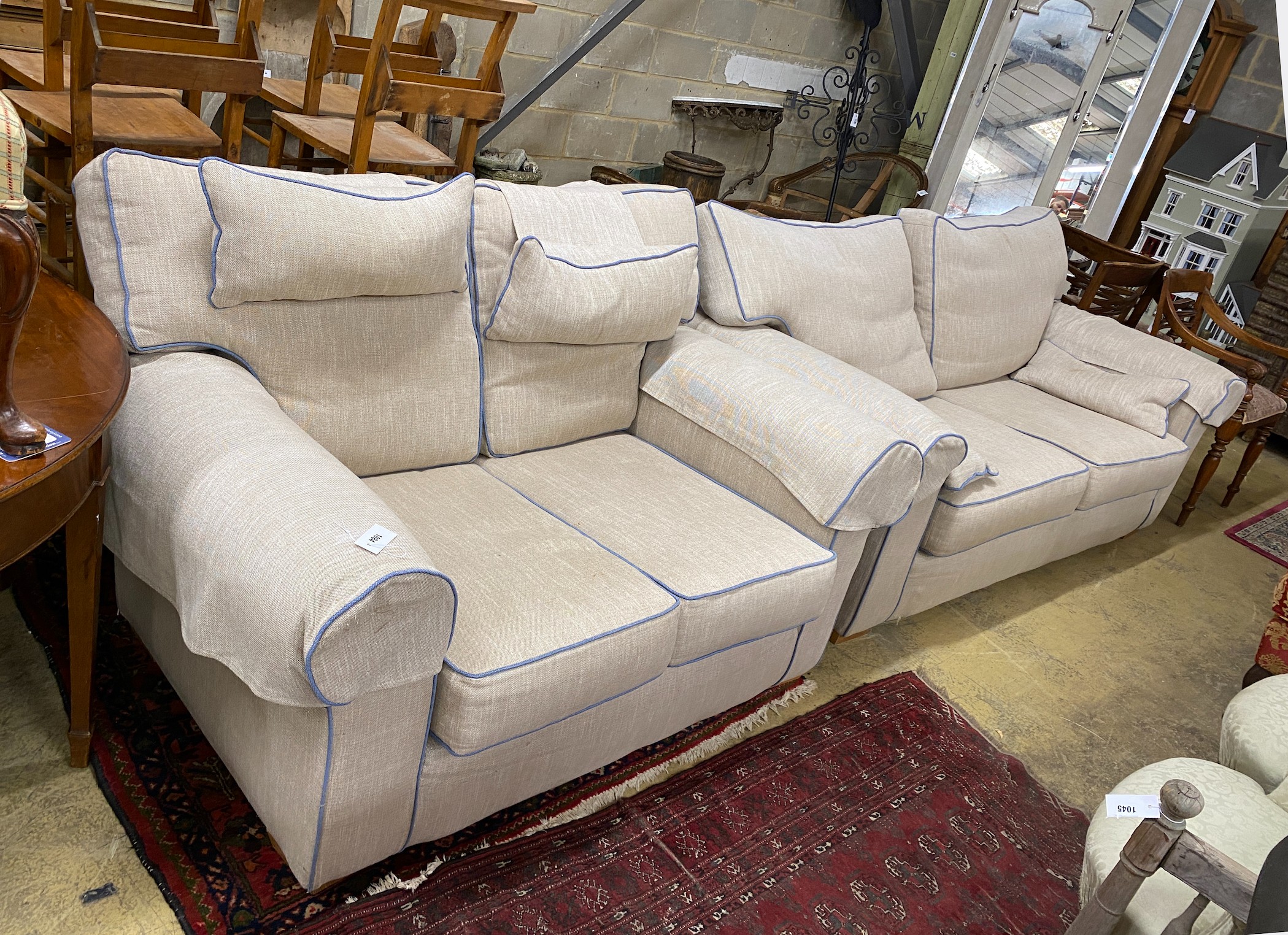 Two cream upholstered settees, with blue corded edging, larger length 200cm, depth 100cm, height 97cm